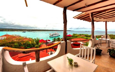 overlooking the balcony of a luxury galapagos hotel on an overcast day with a small ship anchored below