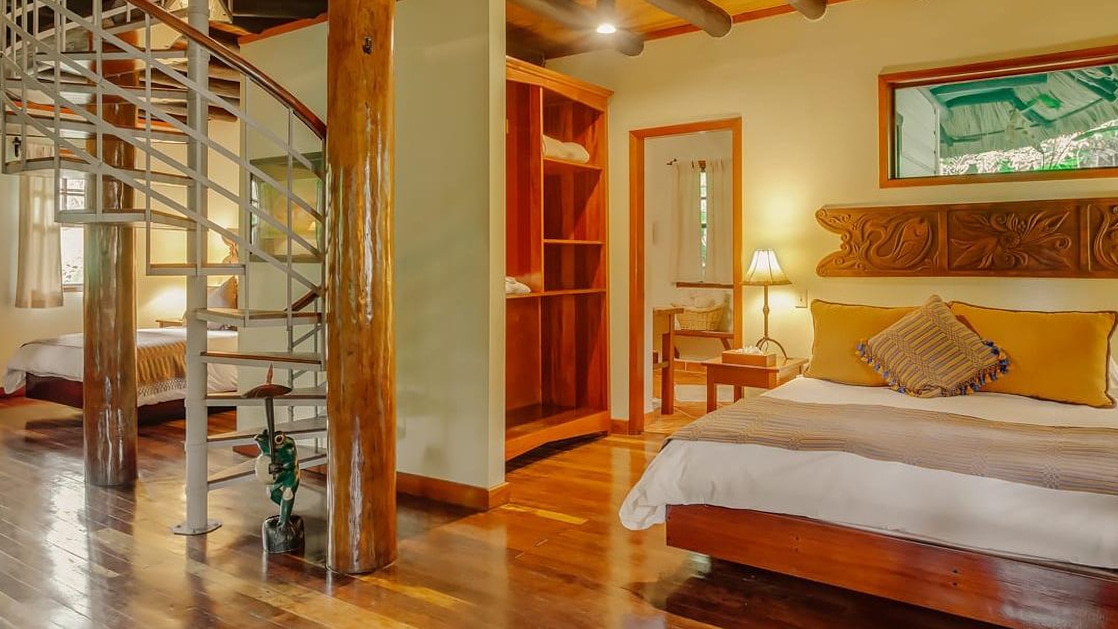 Two bedrooms with wraparound staircase leading to upper-level living area in a villa at Chaa Creek Jungle Lodge in Belize.
