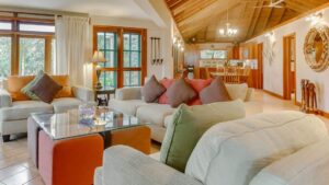 Several couches and lounge chairs in the brightly lit living room of the Spa Villa at Cha Creek in Belize.