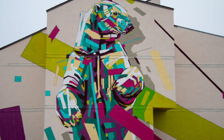 mural of polar bear in bright colors on the side of a tan large building