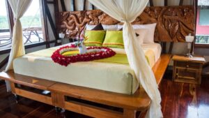 Flowers arranged on a 4-poster king-sized bed with white drapes in the Panoramic Suite at Napo Wildlife Center in the Amazon.