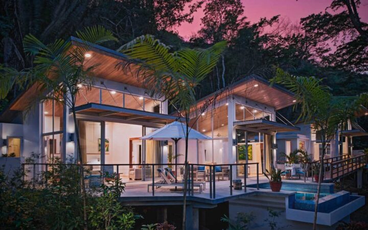 Exterior of Chaa Creek Jungle Lodge at sunset, with large indoor and outdoor living spaces surrounded by lush jungle foliage in Belize