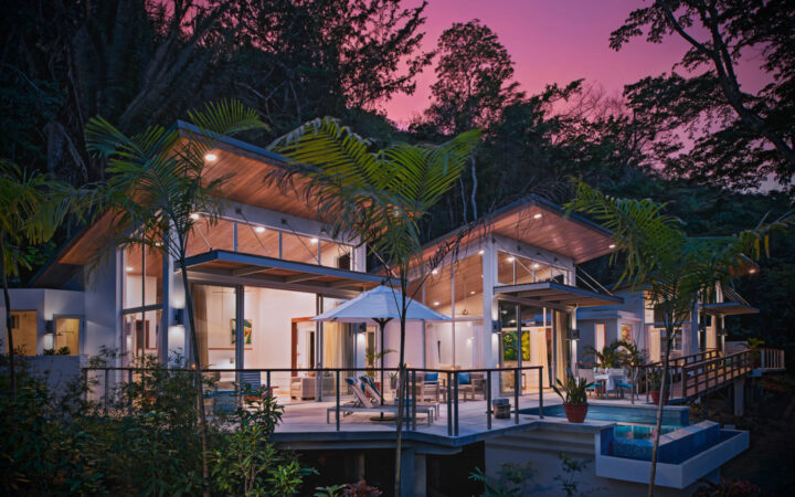 Exterior of Chaa Creek Jungle Lodge at sunset, with large indoor and outdoor living spaces surrounded by lush jungle foliage in Belize