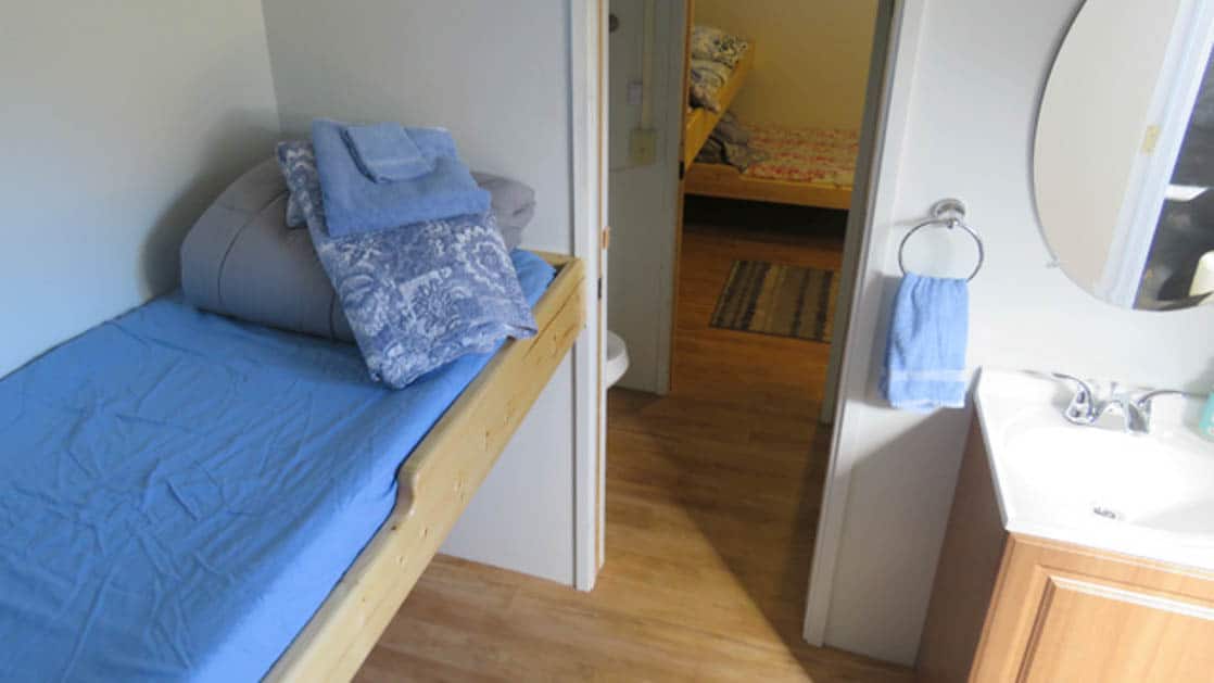 Standard cabin aboard Ursus with twin bed, sink, and door way.