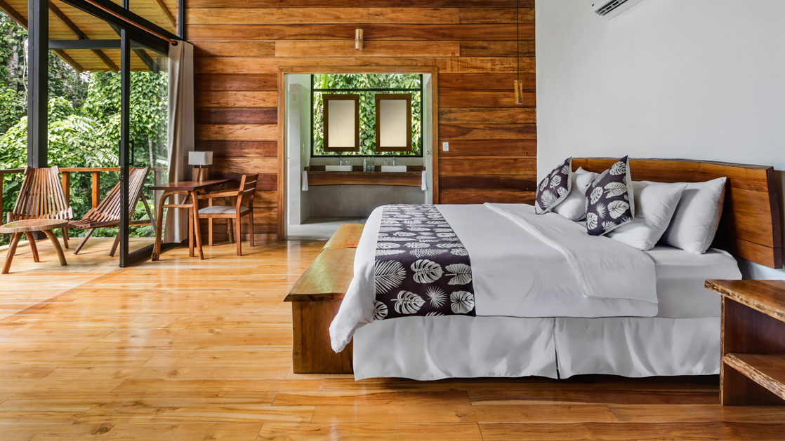 Sacha Lodge suite featuring a king bed balcony with hammock and chairs with lots of light and windows showcasing the jungle