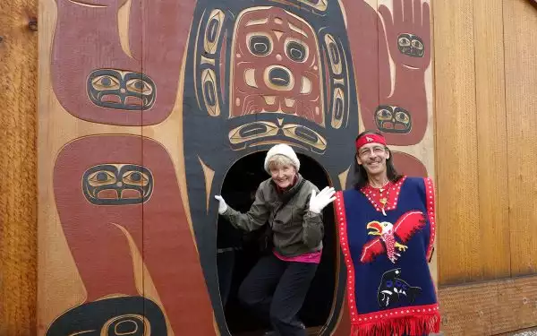 A single female traveler waves from the entrance to a tribal house in Alaska