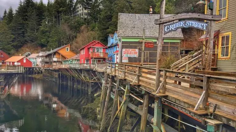 A charming town with wooden walkways, bright colors and tall trees in the background. One of the cultural experiences to be found.