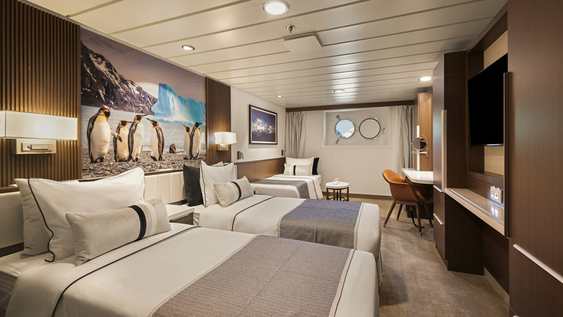 Triple share cabin aboard small ship Douglas Mawson with porthole, desk & 3 twin beds.