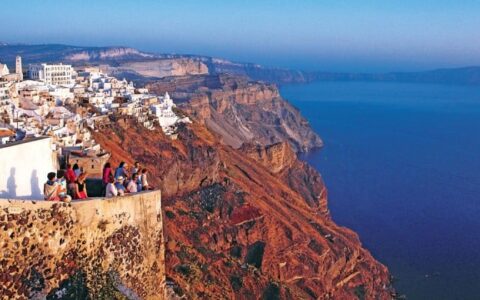 sunset's warm glow illuminates the cliffs and white buildings of santorini