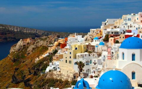 The view of santorini's blue domes and white architecture along the bluffs above the mediterranean as seen from the small ship cruise sailing the greek isles