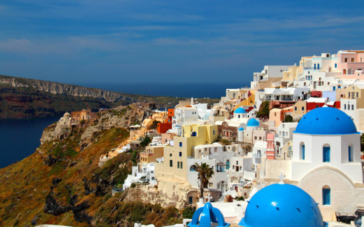 The view of santorini's blue domes and white architecture along the bluffs above the mediterranean as seen from the small ship cruise sailing the greek isles.