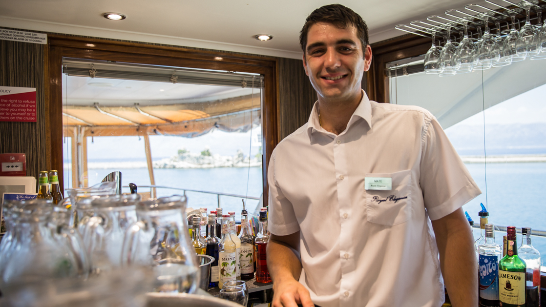 A bartender seen smiling in a white shirt with name tag aboard the Aurora Croatia yacht