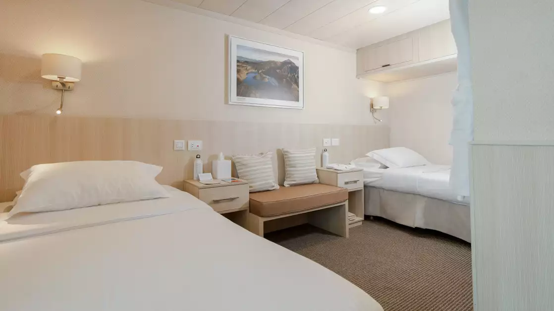 Isabela II stateroom with double bed, chairs, nightstands and reading lights.
