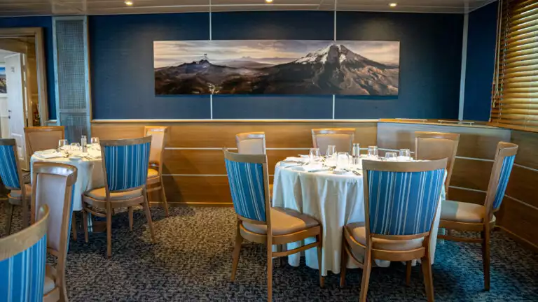 Isabella II dining room with round tables and chairs set up for a meal and buffet service bar.