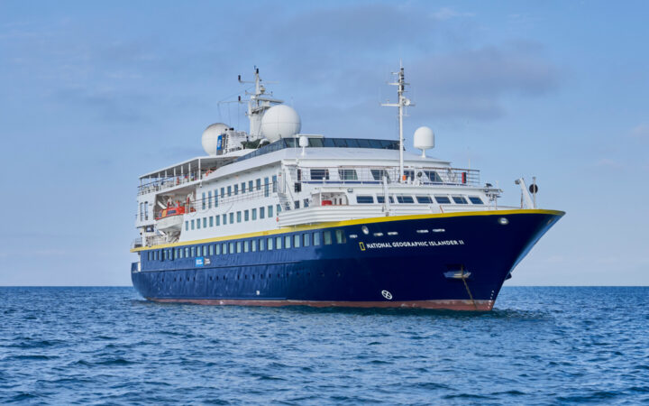National Geographic Islander II Galapagos luxury expedition ship, with dark blue hull, white upper decks & Ecuador flag.