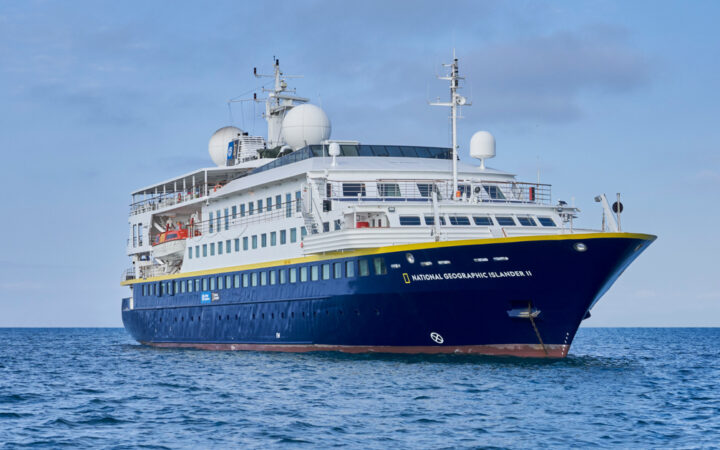 National Geographic Islander II Galapagos luxury expedition ship, with dark blue hull, white upper decks & Ecuador flag.