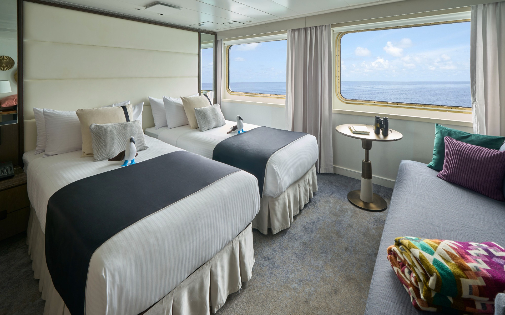 Twin-bed cabin with ocean views aboard a Galapagos luxury expedition ship.