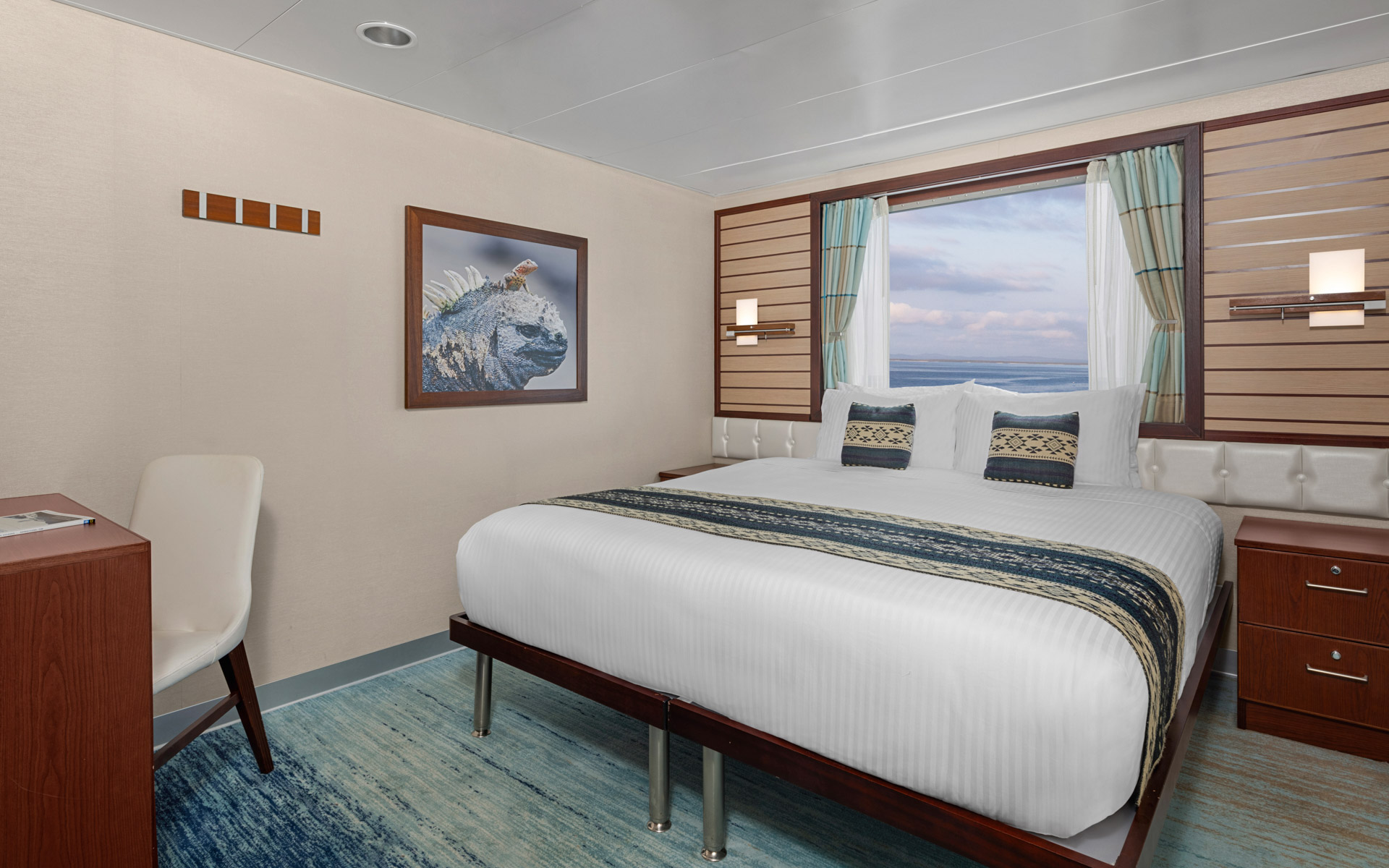Cabin with large bed, armchair, large window aboard National Geographic Endeavour II in the Galapagos Islands