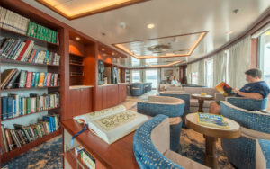 Man reads in armchair beside large window in library aboard National Geographic Endeavour II expedition ship in the Galapagos Islands