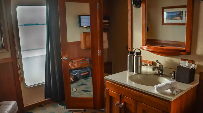 Small cruise bedroom with bathroom attached and brown wood and views to the deck