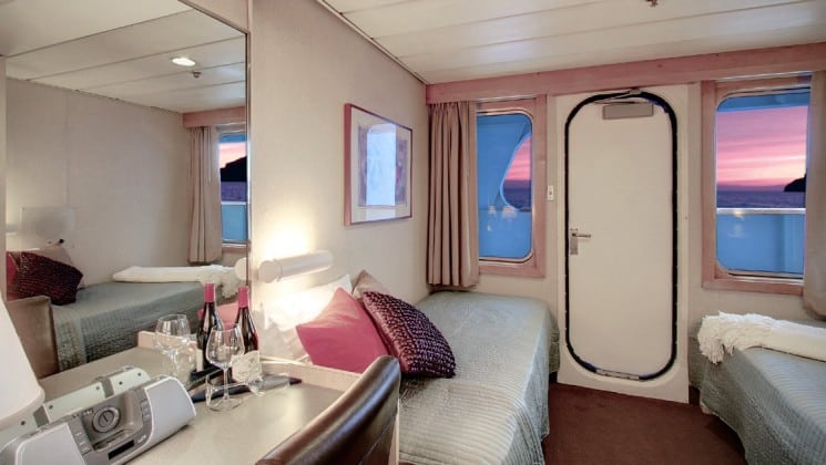 Trailblazer cabin with bed, dresser, window and door leading to a balcony on the safari endeavour Baja small ship