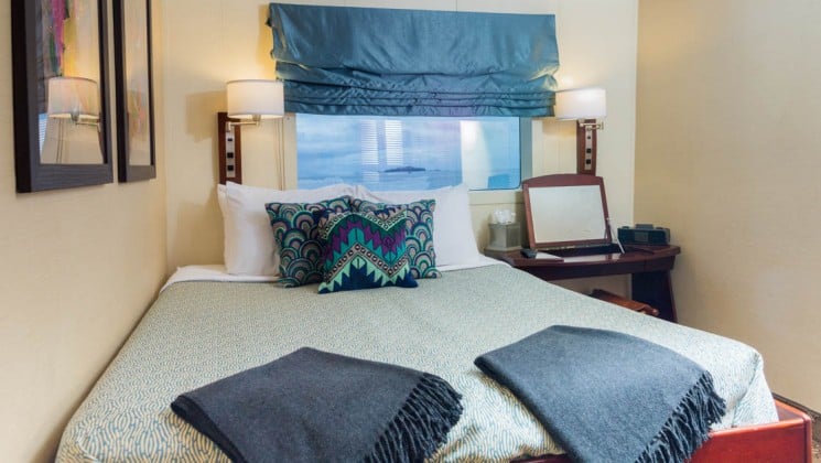 Trailblazer stateroom cabin aboard the Safari Voyager Panama small ship with a large bed, chair and window above the bed