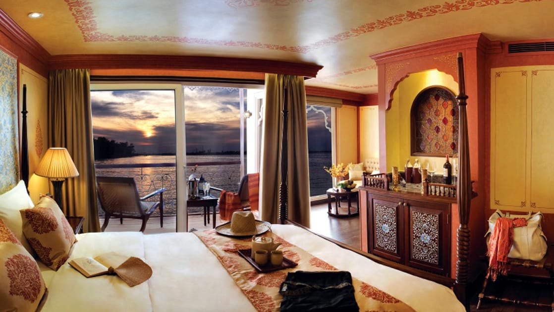 Jahan Category 2 stateroom with queen bed, dresser, balcony with 2 chairs.