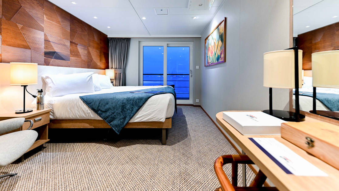Explorer Deck Stateroom aboard Coral Adventurer with desk, bed and veranda.