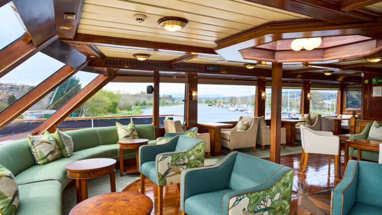 Lord of the Glens lounge area with bar, chairs, couch, tables and large picture windows throughout.