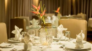 Dining room aboard Amazon riverboat Amatista, with small tables set with white tablecloths, padded beige chairs & floral centerpieces.