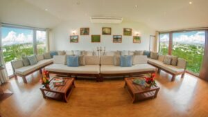 Upper deck lounge on Amatista Amazon riverboat, with wood floor, white walls & couches, wooden coffee tables & view windows.