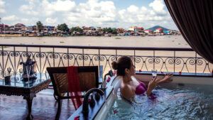 Women laying in luxury bath tub on the balcony of her room aboard a small river boat overlooking the river.