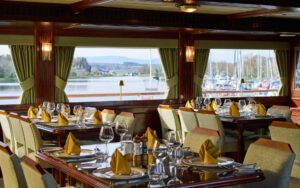 Lord of the Glens dining room with table and chairs, set up for a meal with large picture windows and wood paneling.