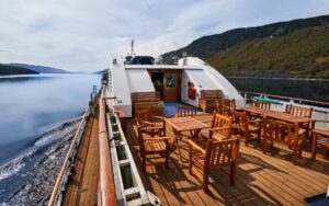 exterior of small ship cruise lord of the glens cruising through a calm passage way with trees on both sides
