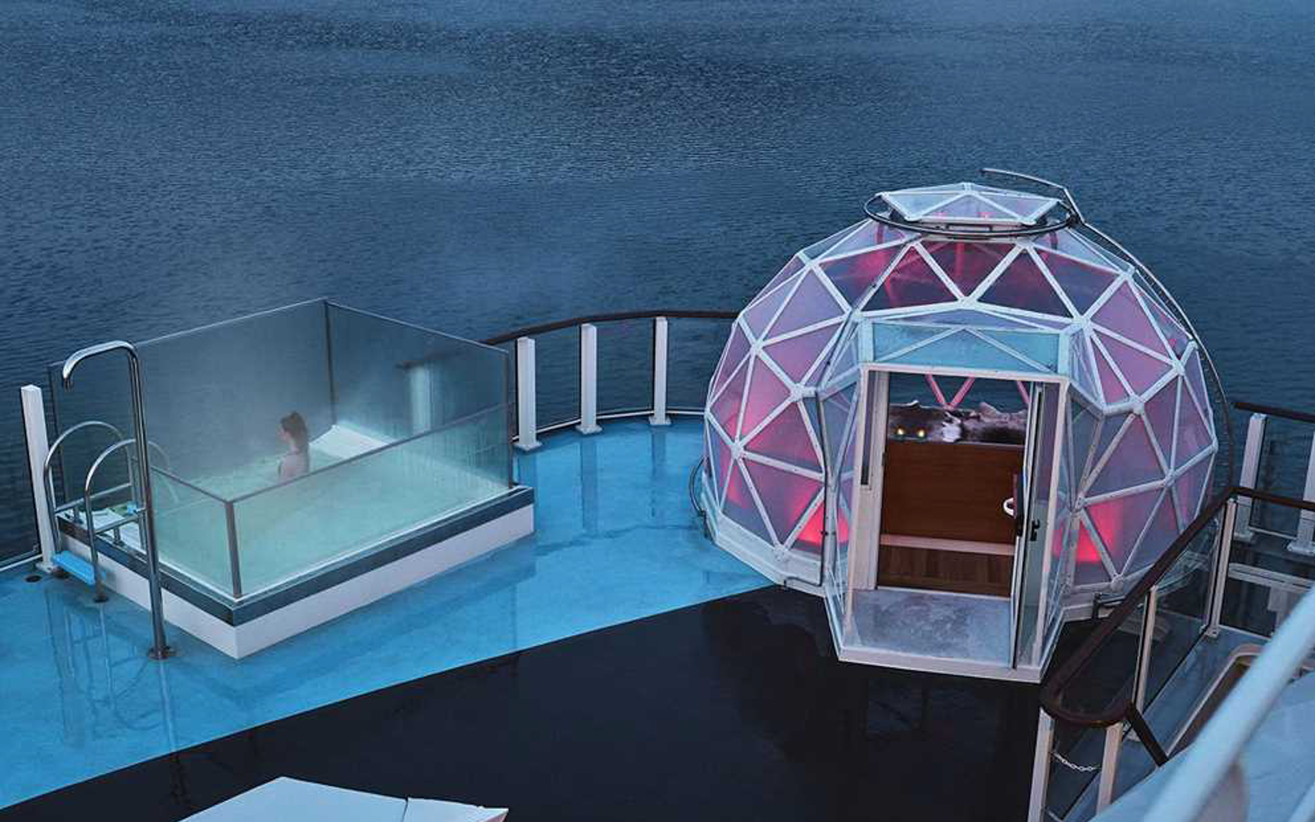 Glass geodesic dome with purple interior lighting sits beside a glass-walled small pool on deck of National Geographic Resolution.