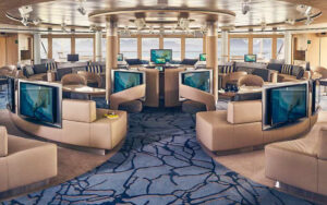 Lounge with couches, chairs, tables, bar and large windows aboard National Geographic Resolution polar expedition ship.