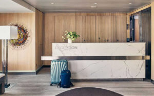White marble reception desk with wood walls behind & blue luggage in front, on Nat Geo Endurance polar expedition ship.
