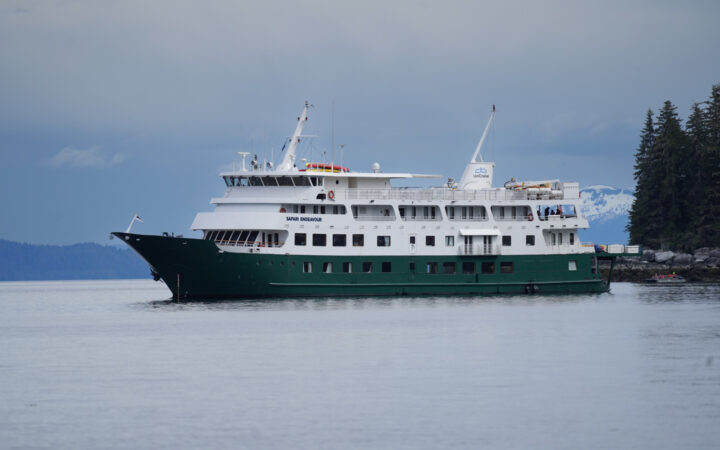 Safari Endeavour small ship cruising on glassy Alaskan waters on a sunny day.