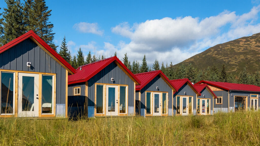 small camp with modern small personal lodges set amongst forest, river, open grassland & large mountains in Alaska.