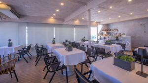 outdoor dining area with white tables and black chairs aboard small cruise ship