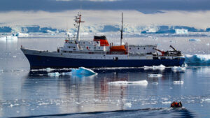 Ushuaia Antarctic ship in ocean with ice bergs nearby and Antarctica behind the ship operated by Antarpply
