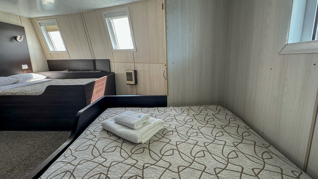 Ushuaia by Antarpply Expeditions to Antarctica featuring a Twin Suite sitting room porthole, and ample space with couch