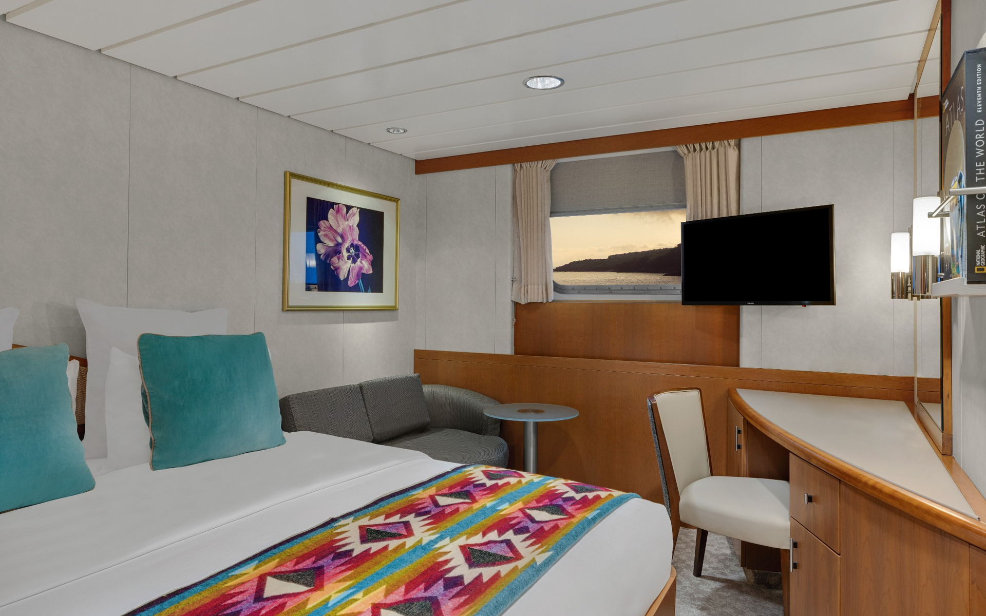 Category 1 cabin with bed, sofa and desk aboard a Galapagos luxury yacht.