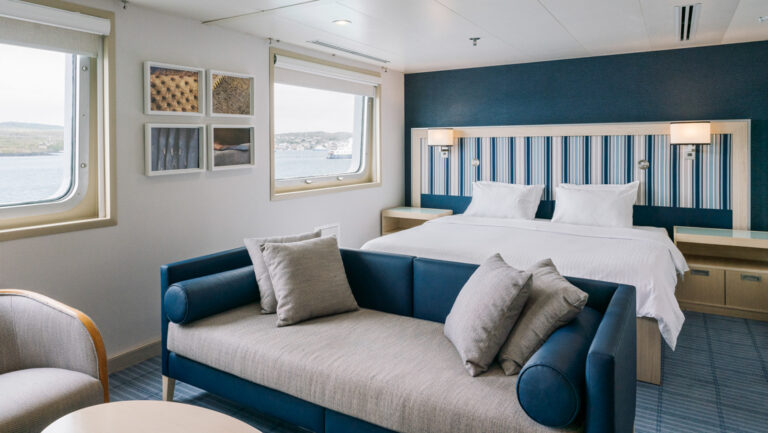 Darwin Suite with a large bed, chaise style couch & seating aboard the Santa Cruz II cruising the Galapagos Isles.