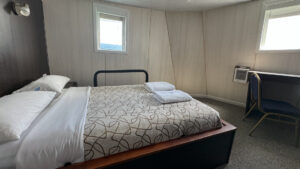 Suite room aboard a small ship cruise with full bed, two small windows and a desk