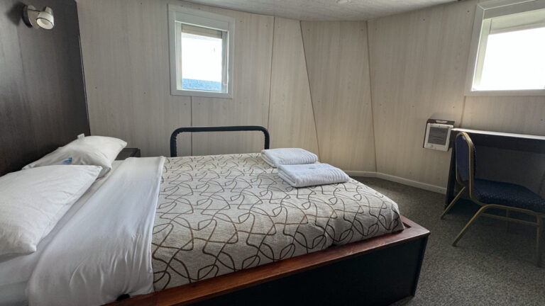 Suite room aboard a small ship cruise with full bed, two small windows and a desk