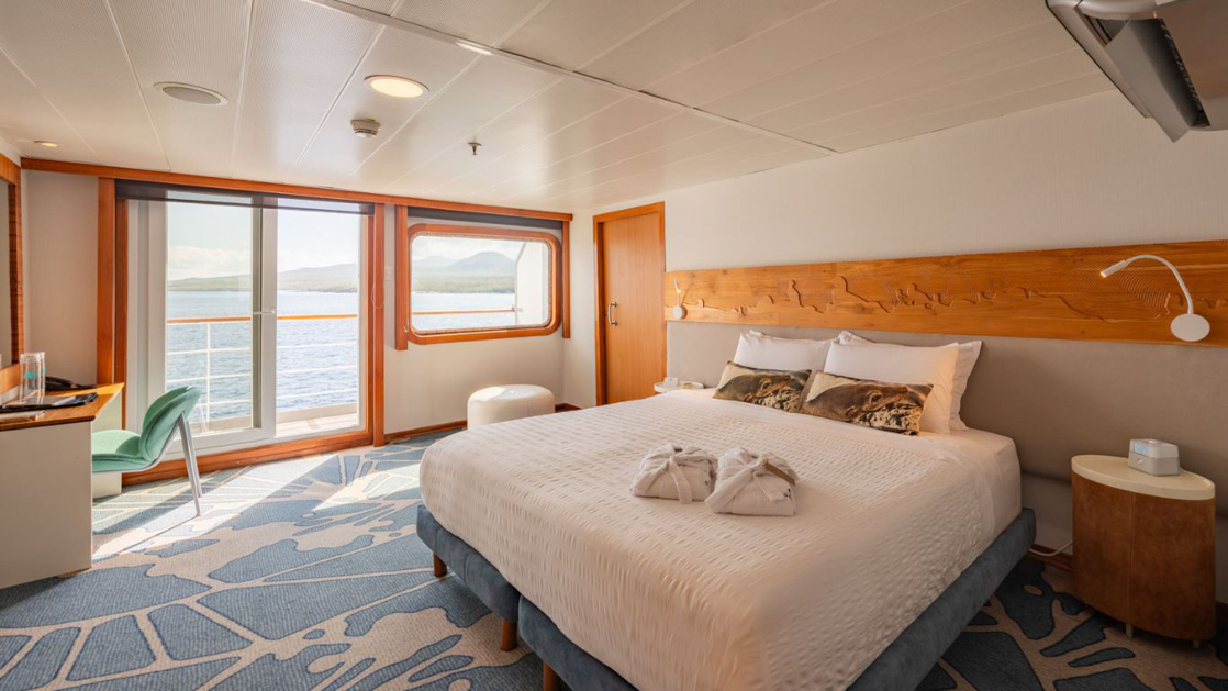 Large Balcony Suite Plus cabin on Galapagos Legend showing king bed, desk and colorful carpet