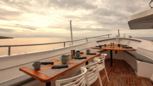 small dining area aboard small cruise ship with place settings and coffee mugs set out on a calm morning.
