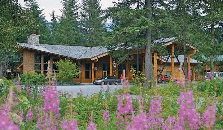 Beneath tall pine trees with lupins and wildflowers in the foreground, the Seward Windsong Lodge is an exceptional Alaska wilderness retreat.