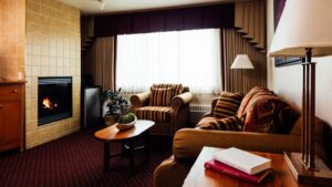 Executive Suite living area with couches and fireplace next to the window at Talkeetna Lodge in Alaska.